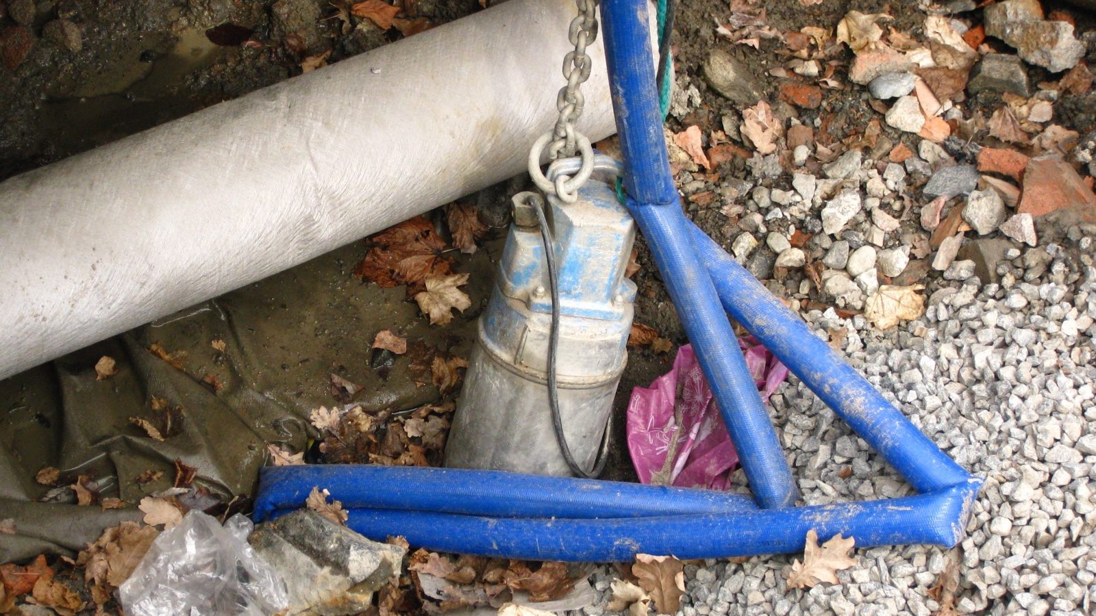 Pompe submersible suspendue à sa chaîne, avec son tuyau de refoulement bleu