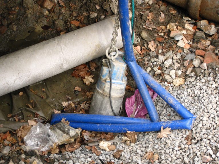 Pompe submersible suspendue à sa chaîne, avec son tuyau de refoulement bleu