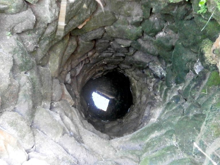 Puits traditionnel en pierre vu du dessus, eau au fond